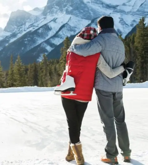 Honeymoon couple embracing in the snow with Himalayan peaks behind them